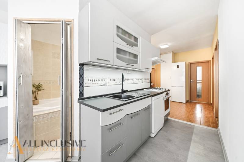 A kitchen in a 3-room apartment with white cabinets and a tiled wall.
