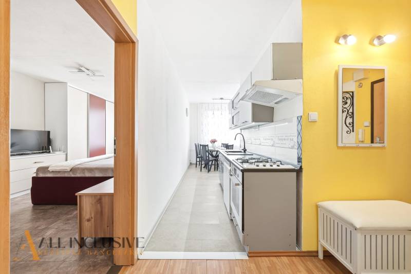 Interior of a 3-room apartment with wood-patterned flooring, kitchen, and bedroom.