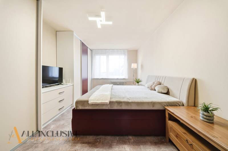 Bedroom in a 3-room apartment with a large bed, wardrobe, and floor with wooden decor.