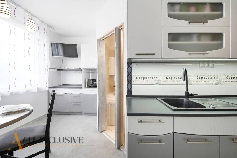 A kitchen in a 3-room apartment with a coffee decor and a dining area.