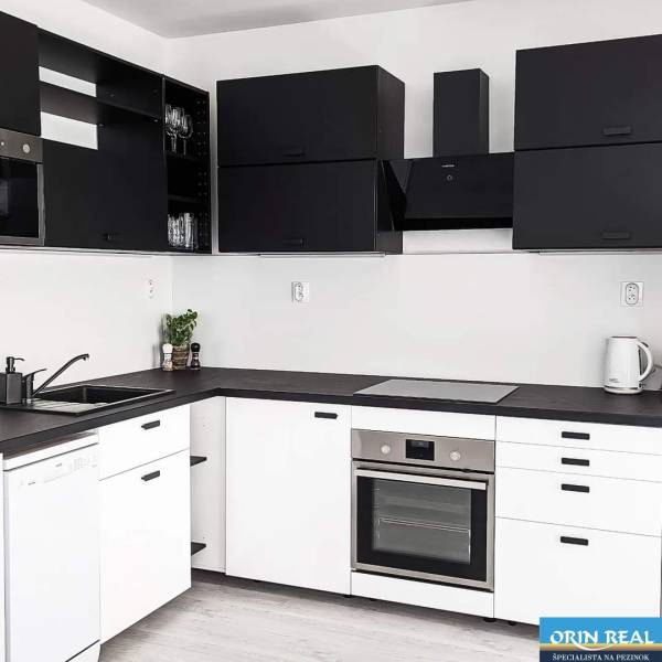 A kitchen in a 2-room apartment with black and white cabinets and built-in appliances.