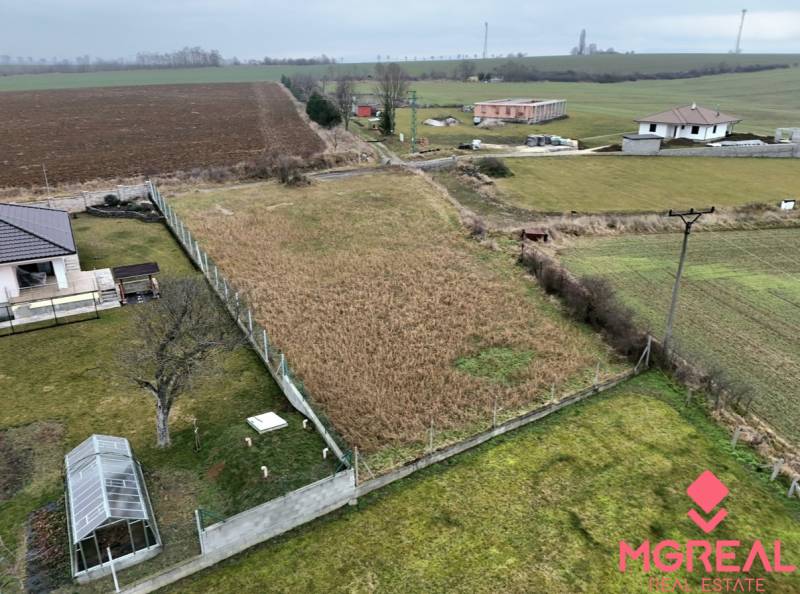 Plots - housing in Kuzmice on a quiet street with overgrown grass and a greenhouse.