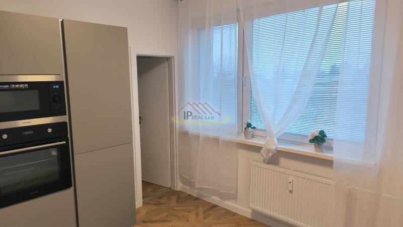 Kitchen in a 4-room apartment with a microwave, large windows, and a wooden decor floor.