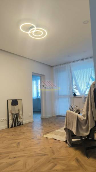 Living room in a 4-room apartment with a wooden decor floor and pendant lighting.