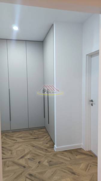 A hallway with white built-in wardrobes and a floor with a wooden decor in a 4-room apartment.
