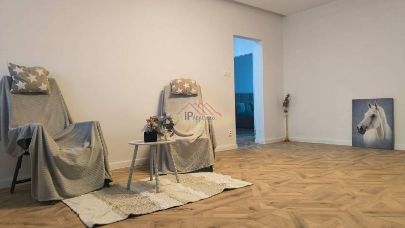 A bright living room with armchairs, a table, and a wooden decor floor in a 4-room apartment.
