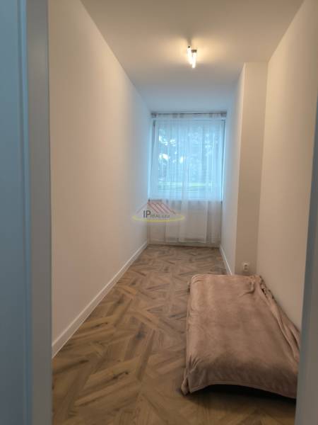 A narrow room with a window and a floor with a wooden decor in a 4-room apartment.