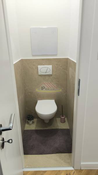 A toilet with a hanging system and a floor with a wooden decor in a 4-room apartment.