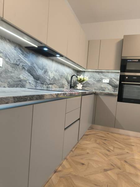 A kitchen in a 4-room apartment with a wood-patterned floor and a stone countertop.