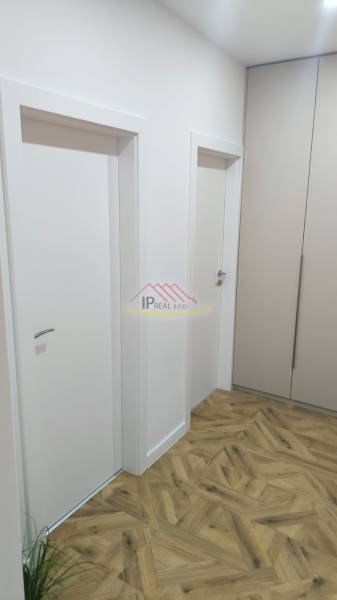 Interior of a 4-room apartment with white doors, cabinets, and a floor with a wood decor.