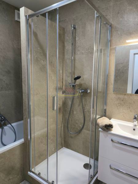 A bathroom with a modern shower and a white sink in a 4-room apartment.