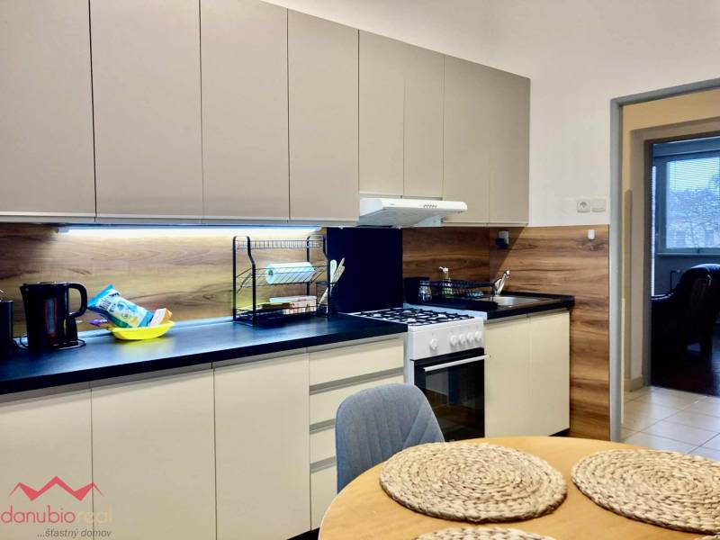 A kitchen in a 3-room apartment with a wooden decor floor and modern equipment.