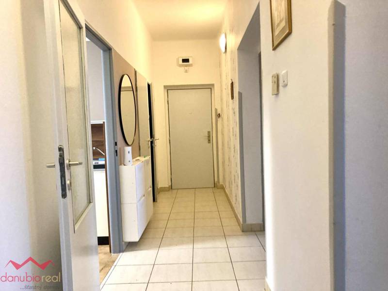 A hallway in a 3-room apartment with light tiles and a mirror on the wall.