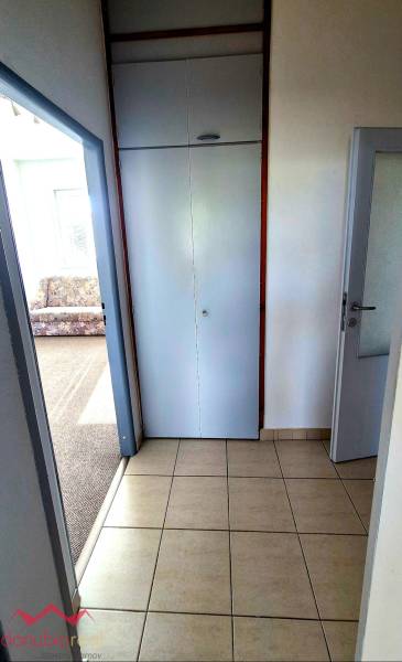 A tiled hallway in a 3-room apartment next to a room with a carpet.