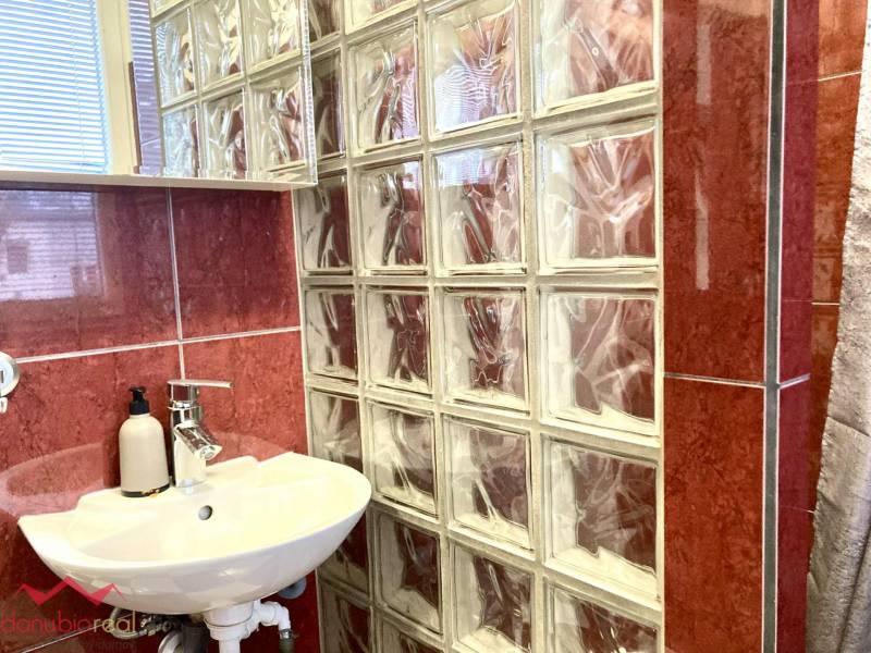 A bathroom in a 3-room apartment with red tiles and a sink next to a glass wall.