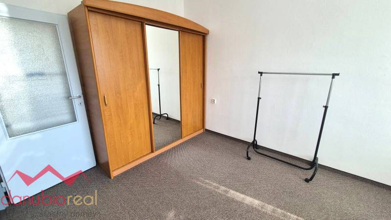 Wooden wardrobe with mirror, space for hangers, carpet in a 3-room apartment.