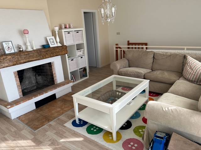 Living room in a cabin with a comfortable sofa, fireplace, and wooden decor flooring.