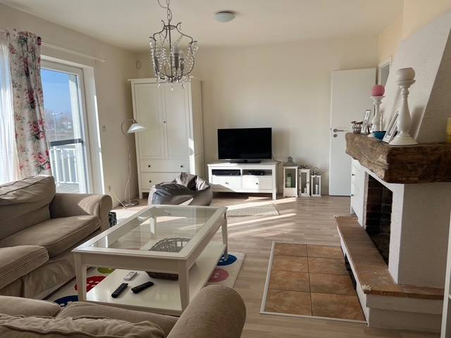 Living room in a cabin with a wood-patterned floor, fireplace, and TV.
