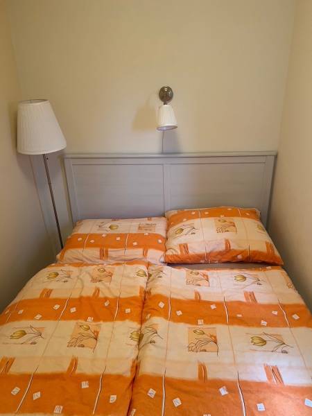 A bed in a cabin with orange-beige bedding and reading lamps.