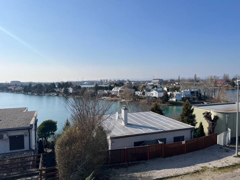 View of the Cottages at Sunny Lakes in Senec surrounded by water and greenery.