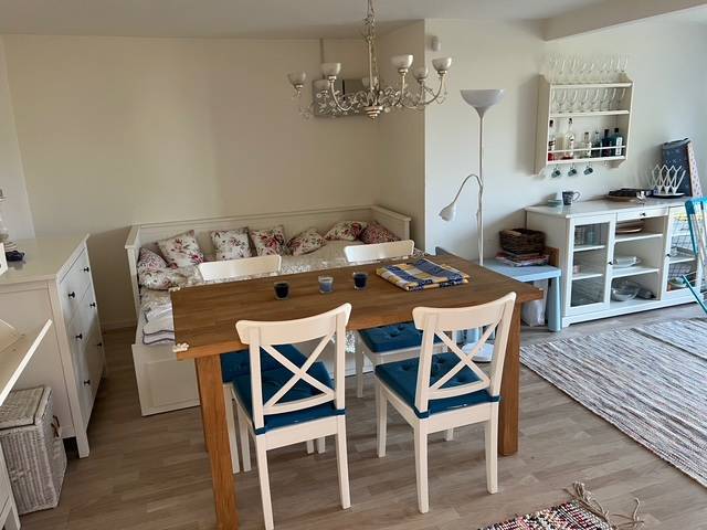 Dining area in the cabin with a wooden table, chairs, and a sofa, floor with a wooden decor.