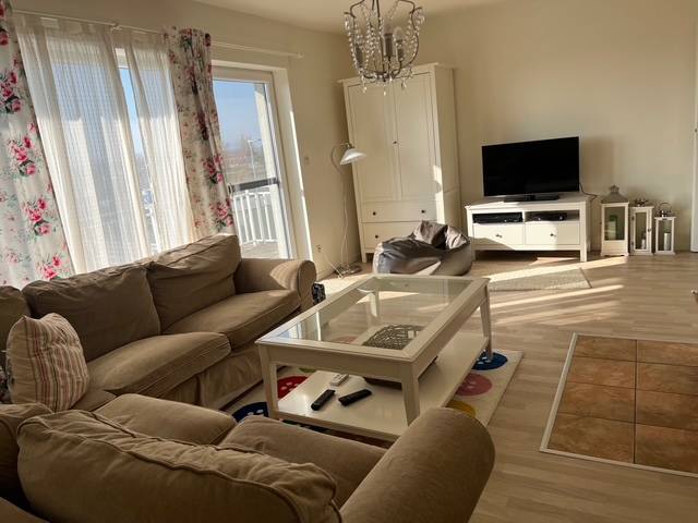 Living area in a cabin with comfortable seating, a television, and a wooden decor floor.