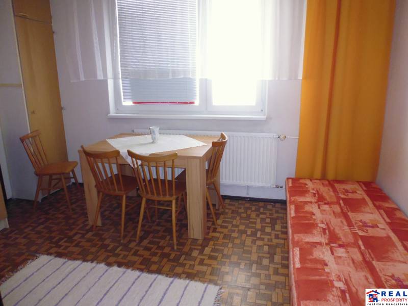 Dining area with wooden chairs and a table in a studio apartment with wooden decor.