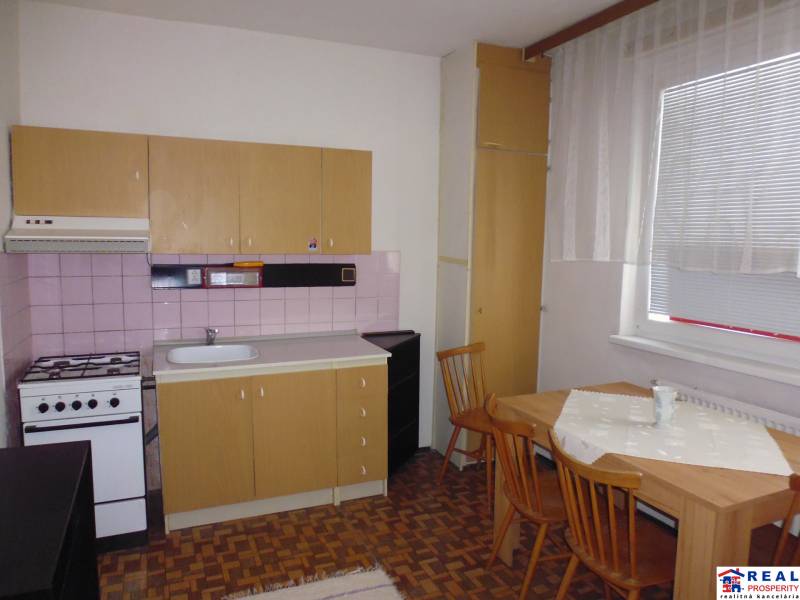 A kitchen in a studio apartment with a simple wooden decor and a dining table.