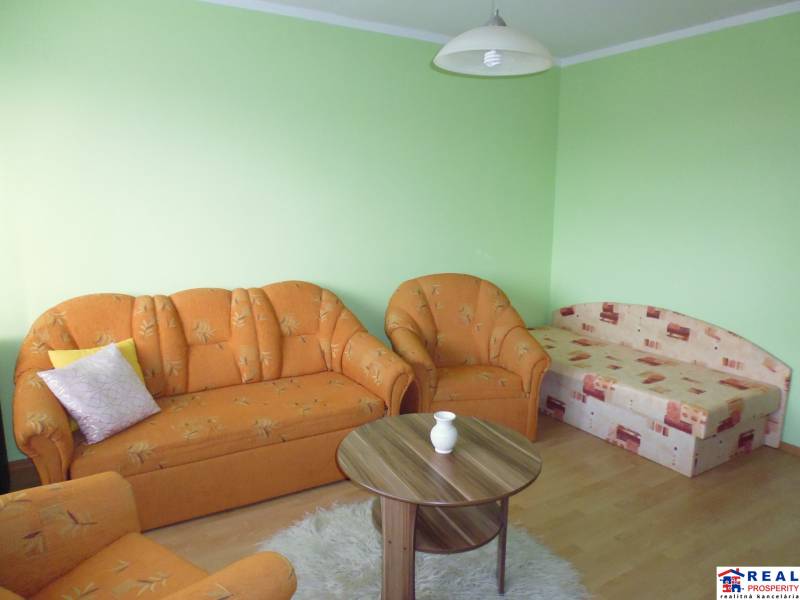 Green walls, an orange sofa, and a wooden decor floor in a studio apartment.