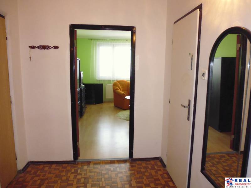 Interior of a 1-room apartment with a wooden decor floor and a comfortable armchair.