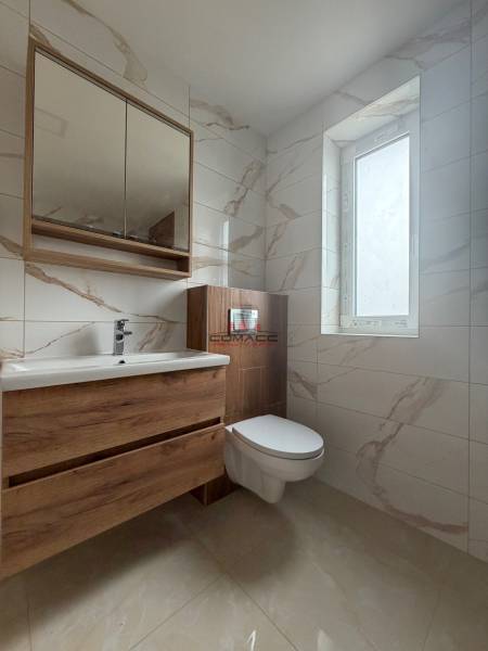 A bathroom in a family house with a mirror, a sink, and ceramic tiles.