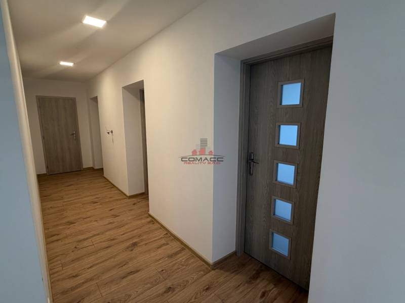 A hallway in a family house with a wood-patterned floor and wooden doors.