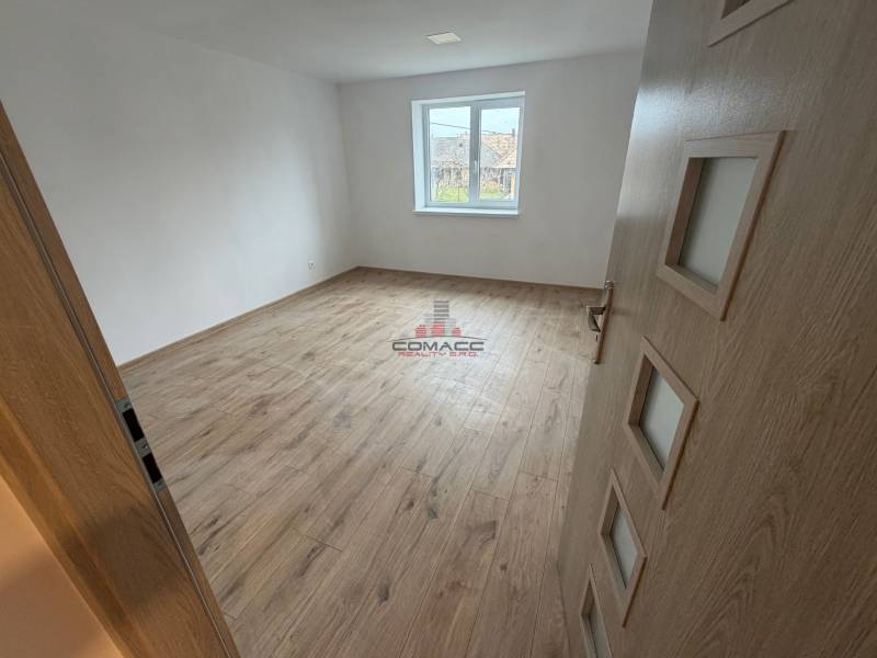 A room in a family house with a wooden decor floor and white walls.