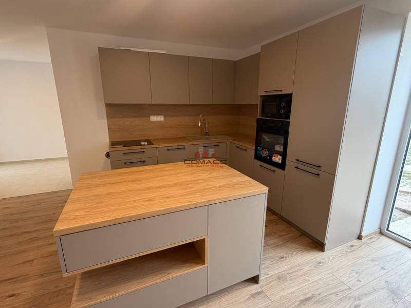 A kitchen in a family house with a wooden decor floor and kitchen cabinets.