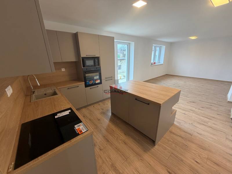 A kitchen in a family house with a wooden decor floor, bright and spacious layout.