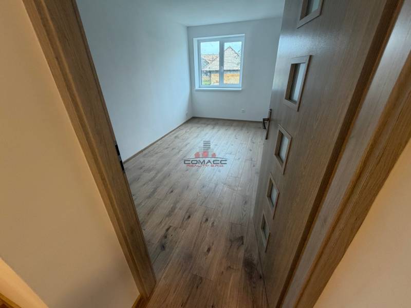 A room in a family house with a wooden decor floor and a large window.