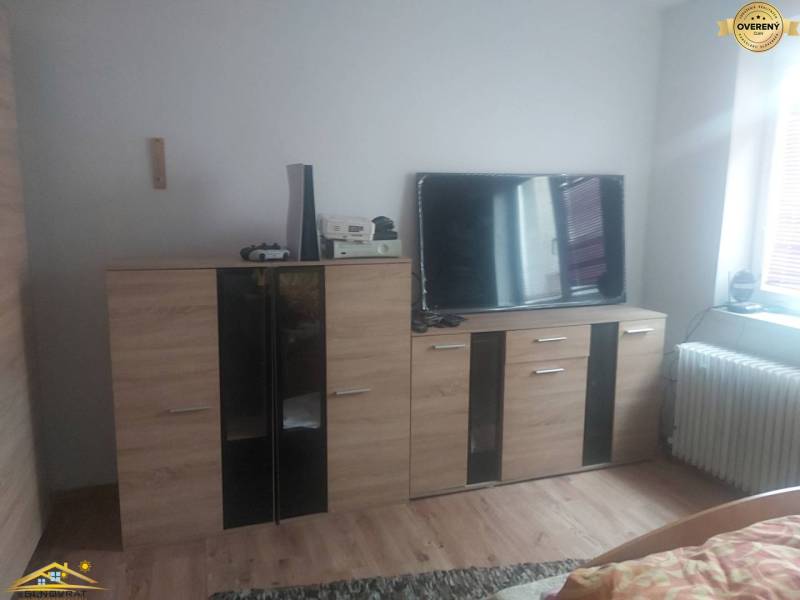 Living room in a family house with furniture, a television, and a wooden decor floor.