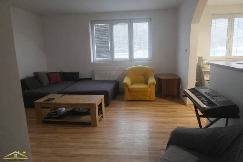 Living room in a family house with a wooden decor floor, a sofa, and a piano.