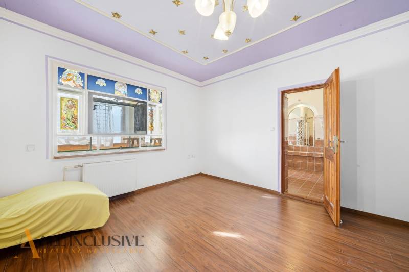 A room with a wooden decor floor, stained glass windows, open doors to the bathroom.