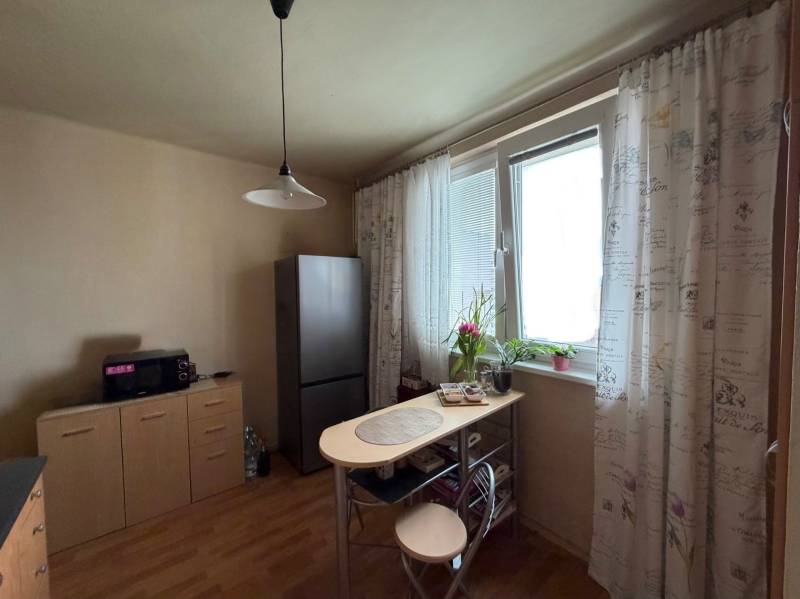 Dining nook with a window and a wooden decor floor in a 3-room apartment.