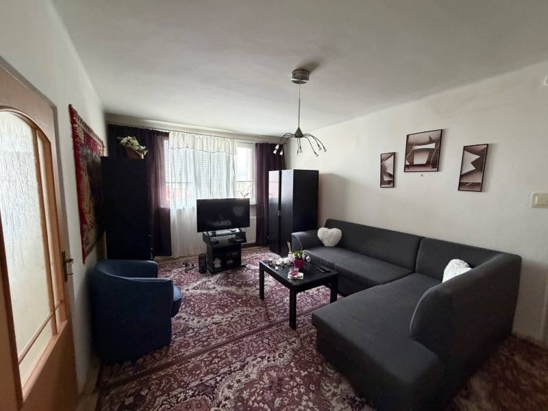 Living room with a corner sofa, carpet, and television in a 3-room apartment.