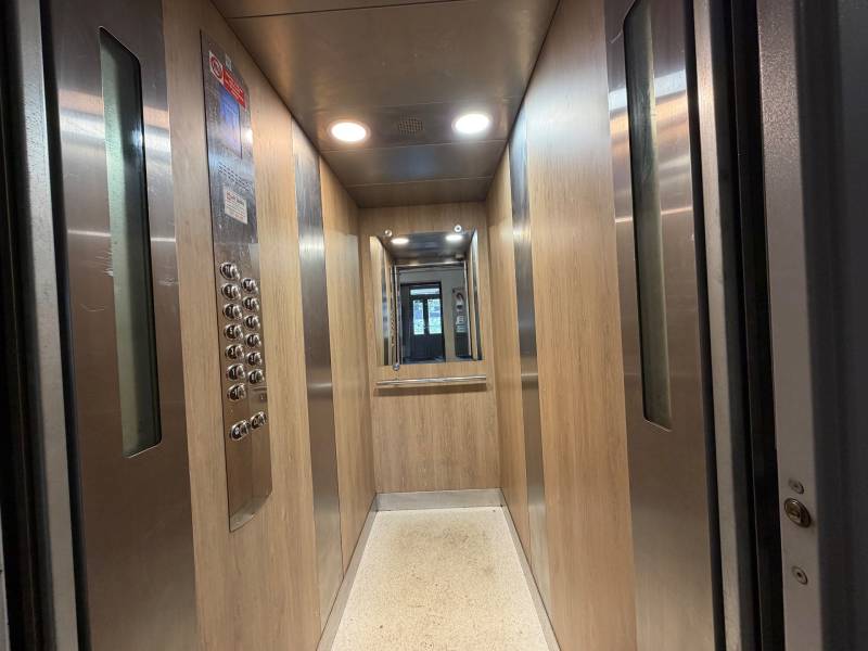 Interior of an elevator with wood decor and a mirror, in a multifunctional building.