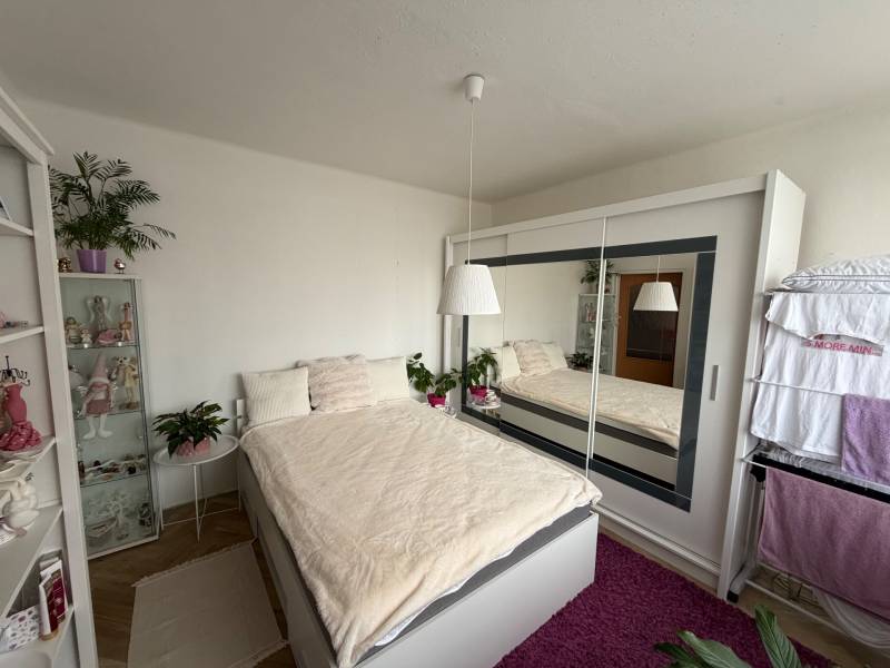 A bedroom in a 3-room apartment with a large built-in wardrobe and a floor with a wooden decor.