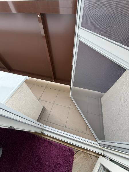 Balcony in a 3-room apartment with tiles and a carpet by the door.