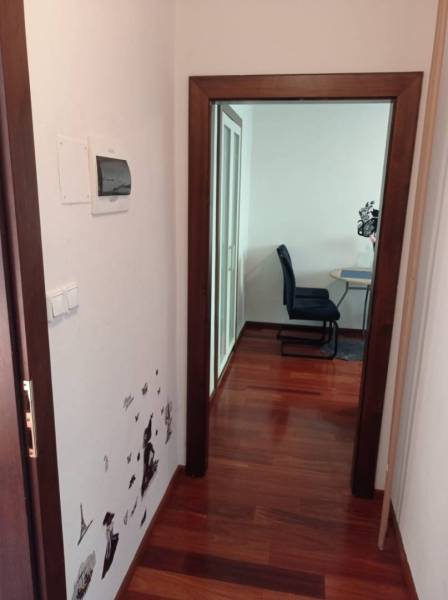 A hallway in a 2-room apartment with wall decor and a floor with a wood design.
