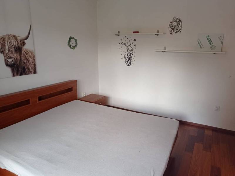 Bedroom with a large bed, wooden decor, and minimalist wall decorations in a two-room apartment.