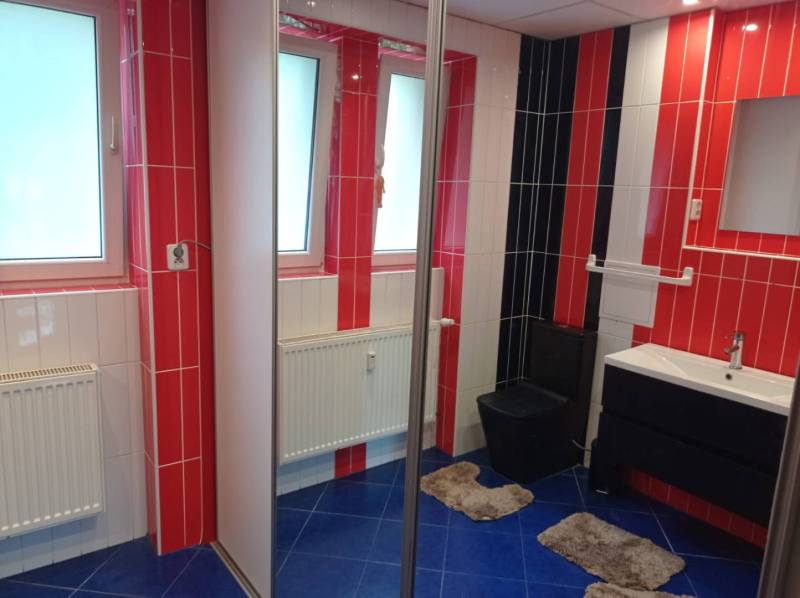A bathroom with colorful tiles and a sink in a 2-room apartment.