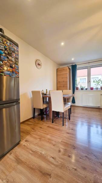 A dining room with a wood-patterned floor in a two-room apartment, a table and chairs by the window.