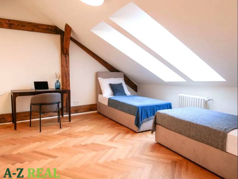 Attic room in a 3-room apartment with skylights, a work desk, and beds.