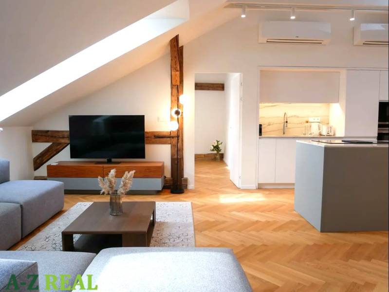 Attic living space with wood-patterned flooring, TV, and kitchen in a 3-room apartment.